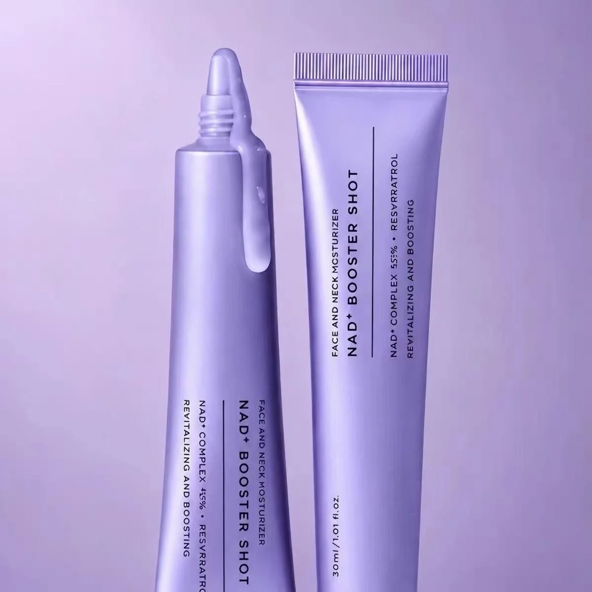 Two lavender cosmetic tubes on a matching lavender background, one with a pointed applicator tip and one labeled 'NAD+ BOOSTER SHOT' with additional text including 'FACE AND NECK MOISTURIZERS' and 'RESVERATROL'.