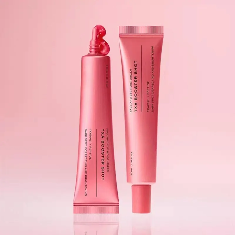 Two pink cosmetic tubes and a matching squeeze bottle labeled T+AA BOOSTER SHOT, arranged on a soft pink reflective studio background.