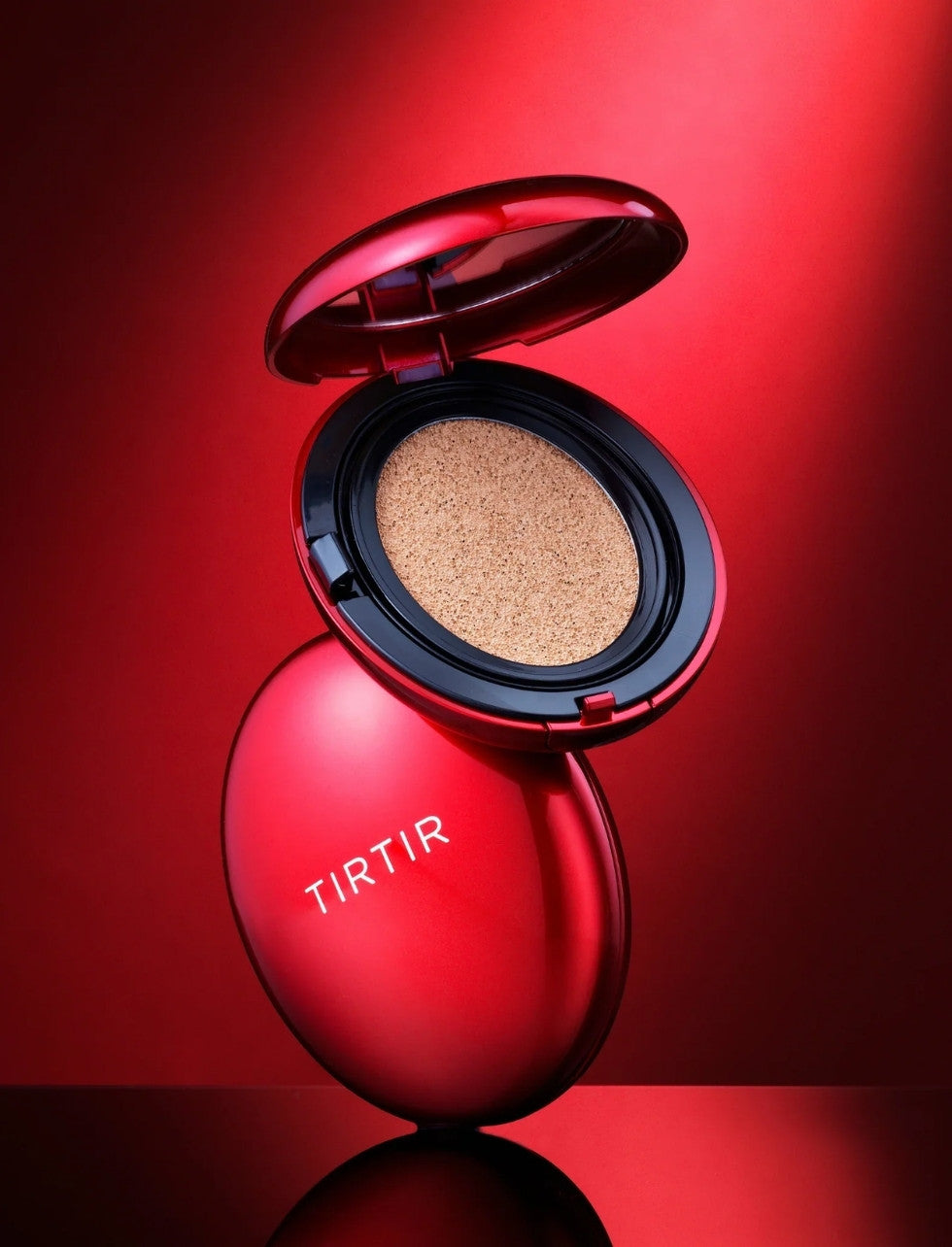 Open cosmetic compact with beige powder on a red background, featuring the brand 'TIRTIR'.