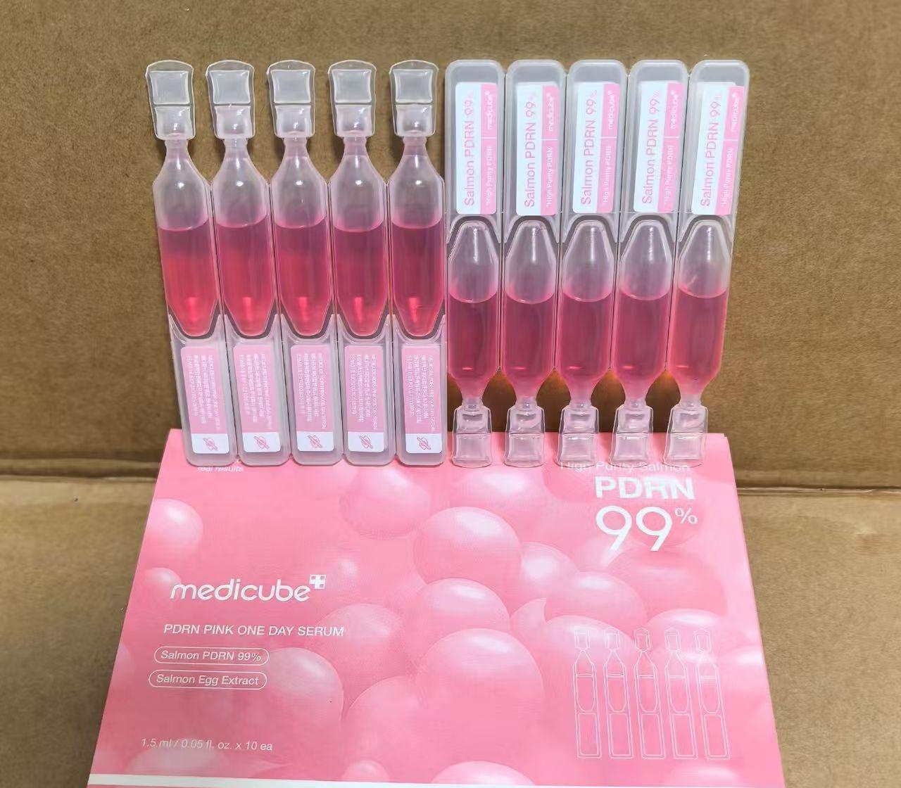 A set of Medicube PDRN 99% Florn Pink One Day Serum ampoules arranged on top of their retail display box, photographed against a brown cardboard background.