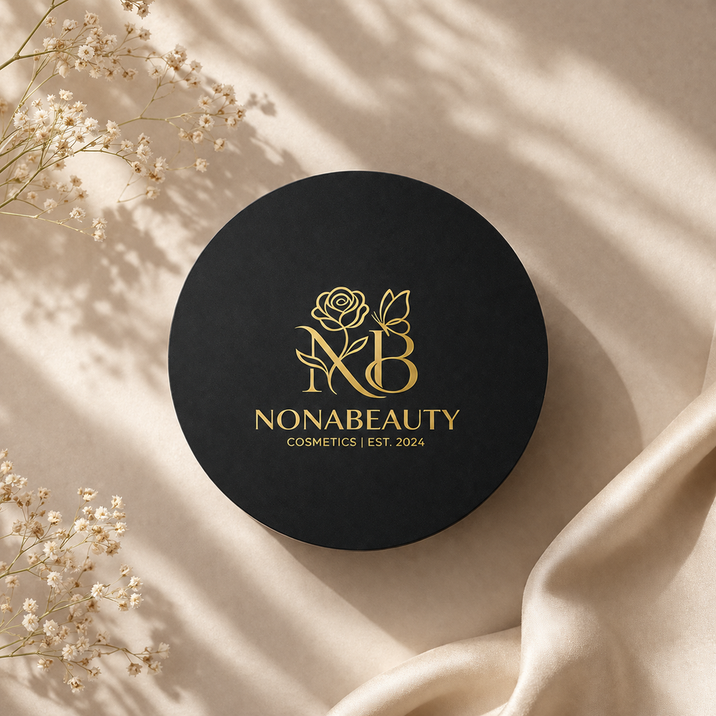 A round black cosmetic box lid with gold Nonabeauty branding, styled on a beige fabric background with dried flowers and soft shadows.